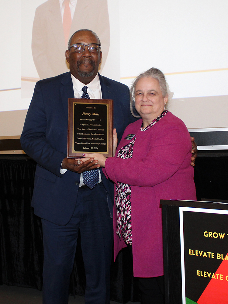 Retired Economic Development Director Harry Mills accepts a plaque from VGCC President Dr. Rachel Desmarais to honor his years of service to Granville County.